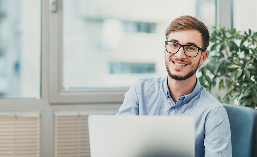 Man smiling behind a laptop